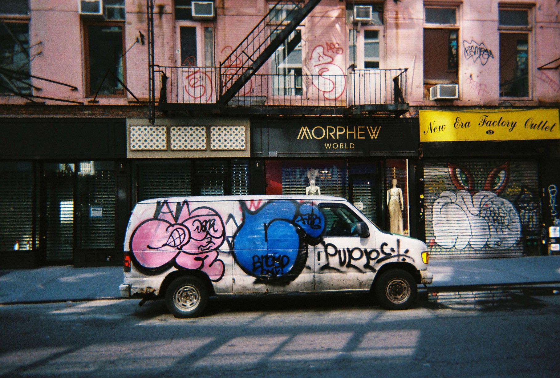 A graffiti-covered van parked on a Chinatown street